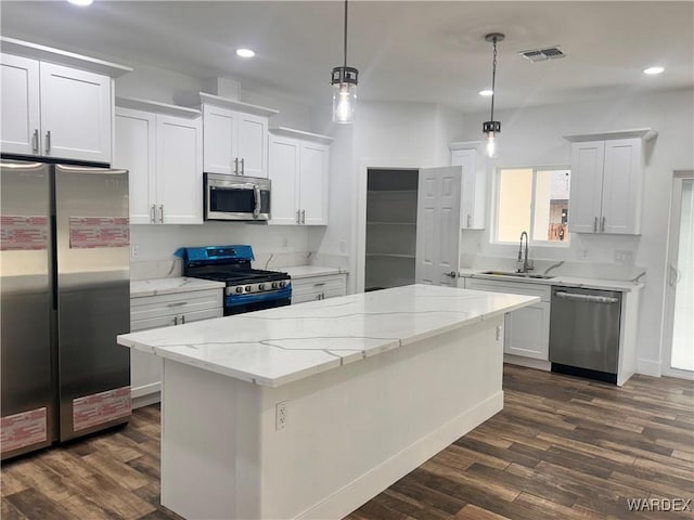 kitchen with appliances with stainless steel finishes, pendant lighting, white cabinets, and a sink