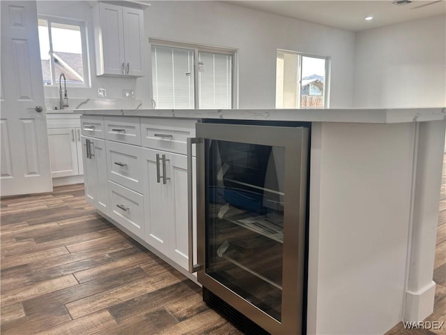 kitchen featuring dark wood finished floors, recessed lighting, white cabinets, a sink, and beverage cooler