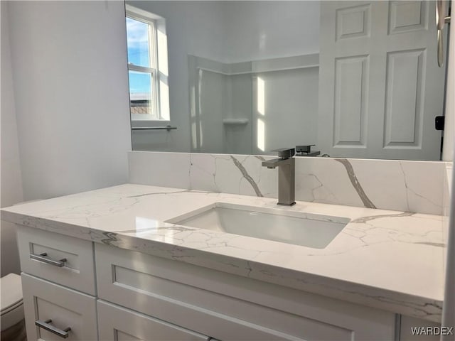 bathroom with backsplash, vanity, and toilet