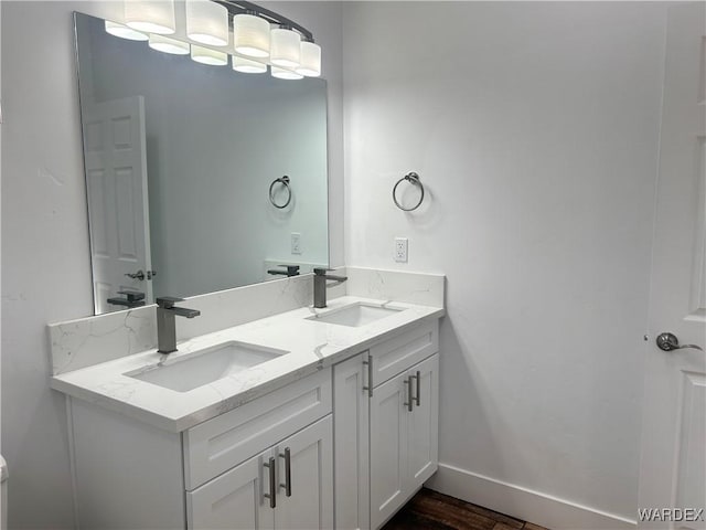 bathroom featuring double vanity, baseboards, and a sink