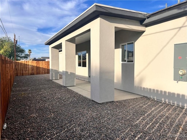 view of side of property with a fenced backyard, a patio, and stucco siding