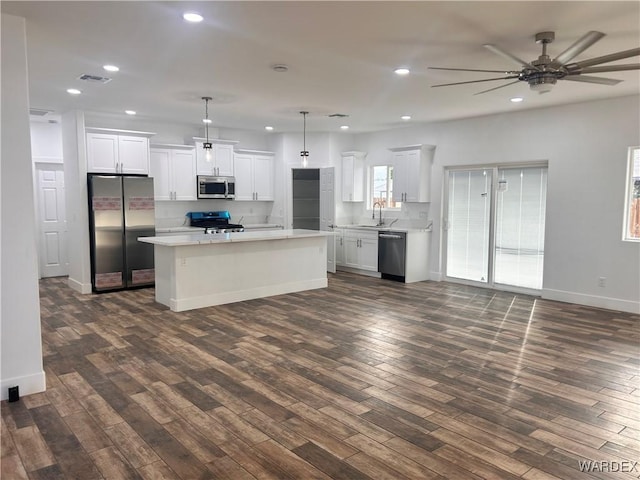 kitchen featuring a kitchen island, white cabinetry, hanging light fixtures, appliances with stainless steel finishes, and light countertops