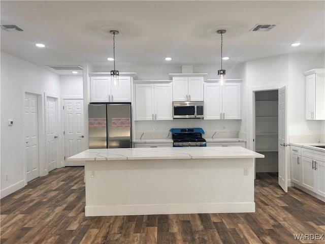 kitchen with appliances with stainless steel finishes, a center island, white cabinets, and decorative light fixtures