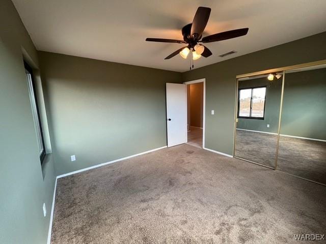 unfurnished bedroom featuring carpet floors, a ceiling fan, visible vents, baseboards, and a closet