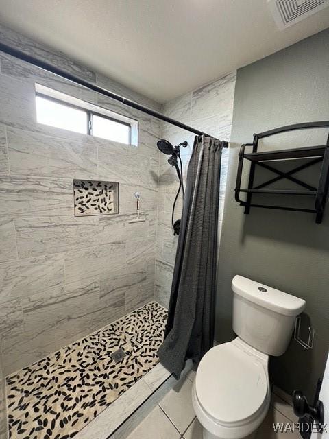 bathroom featuring toilet, a shower stall, and visible vents