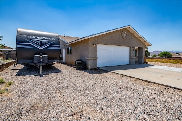 view of side of property featuring a garage, a mountain view, concrete driveway, and stucco siding