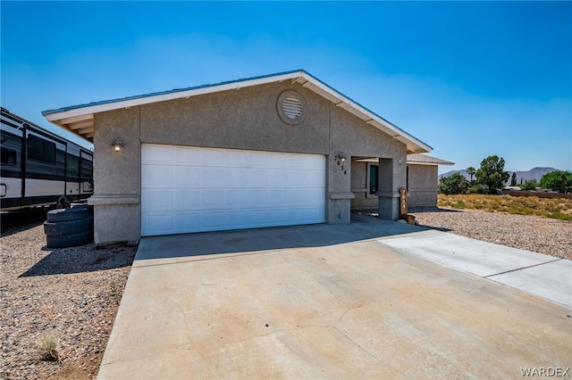 ranch-style home featuring driveway, a garage, and stucco siding