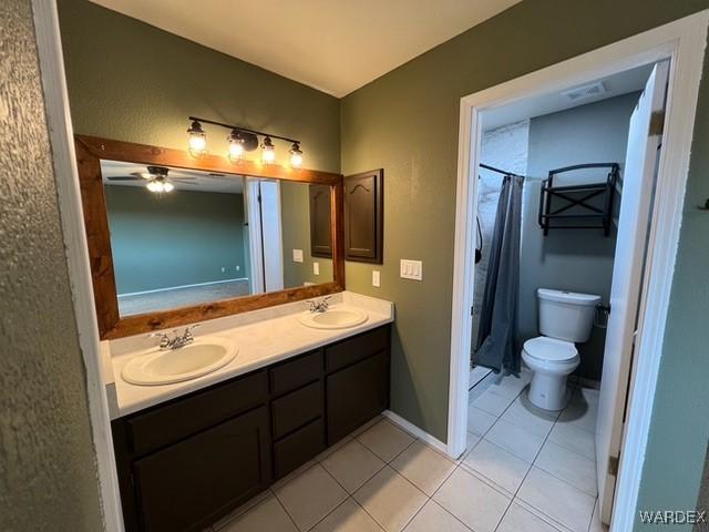 bathroom with tile patterned floors, a sink, toilet, and double vanity