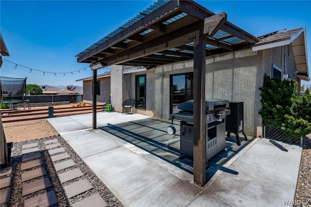 view of patio with a trampoline, grilling area, and fence