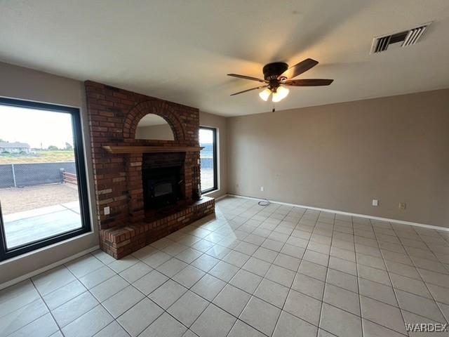 unfurnished living room with light tile patterned floors, a wealth of natural light, and visible vents