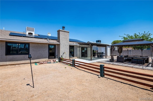 rear view of property featuring fence, a gazebo, a patio area, an outdoor living space, and stucco siding