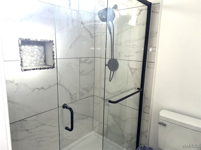 bathroom featuring toilet and a marble finish shower