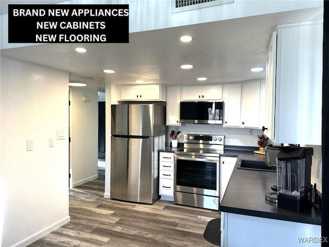 kitchen featuring dark countertops, visible vents, appliances with stainless steel finishes, and white cabinets