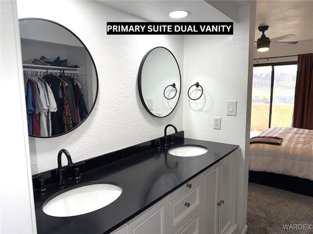 bathroom featuring a textured wall, a sink, ensuite bathroom, and double vanity