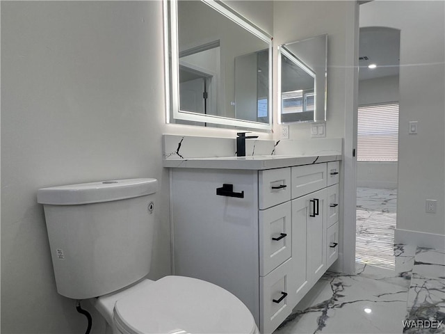 bathroom with toilet, marble finish floor, and vanity