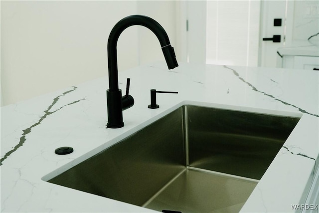 details with light stone counters, white cabinets, and a sink