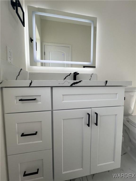 bathroom with marble finish floor, vanity, and toilet