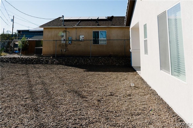 view of property exterior with fence, solar panels, and stucco siding