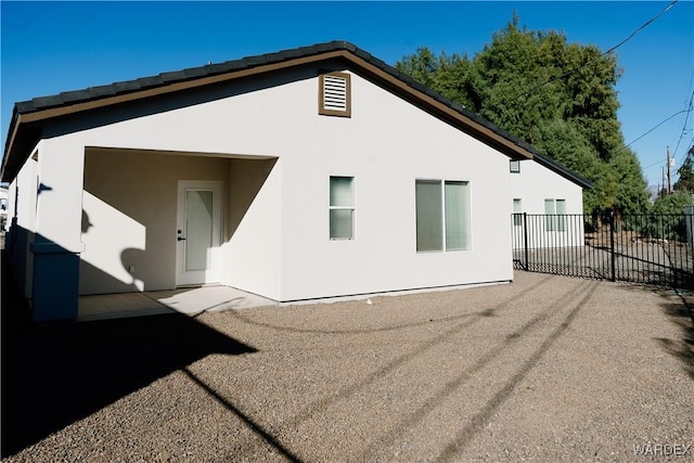 rear view of house featuring fence, a patio, and stucco siding