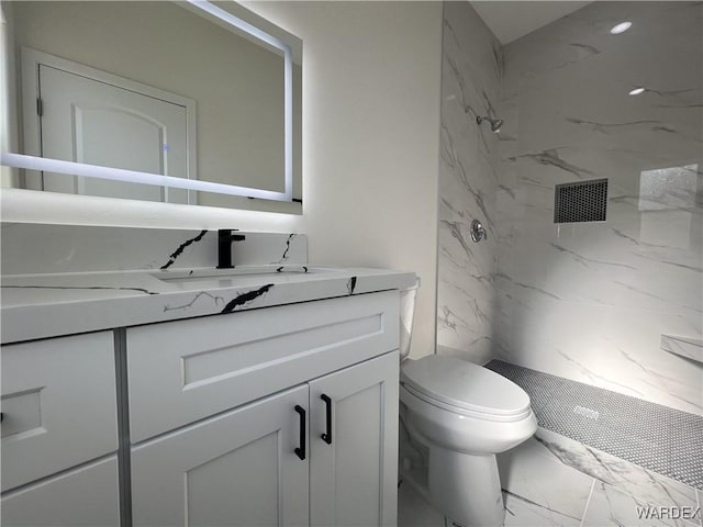 bathroom with marble finish floor, toilet, vanity, and a marble finish shower