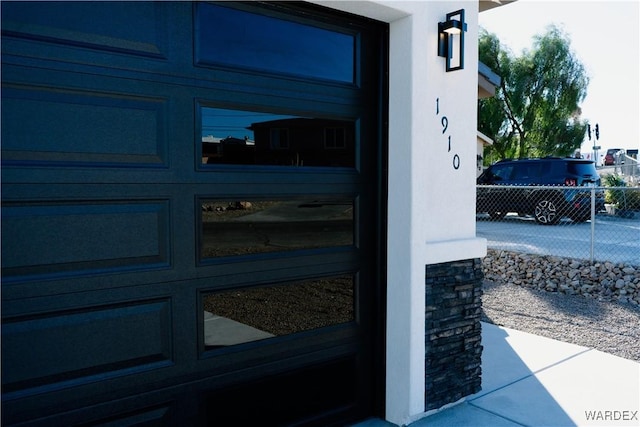 entrance to property featuring a garage, fence, and stucco siding