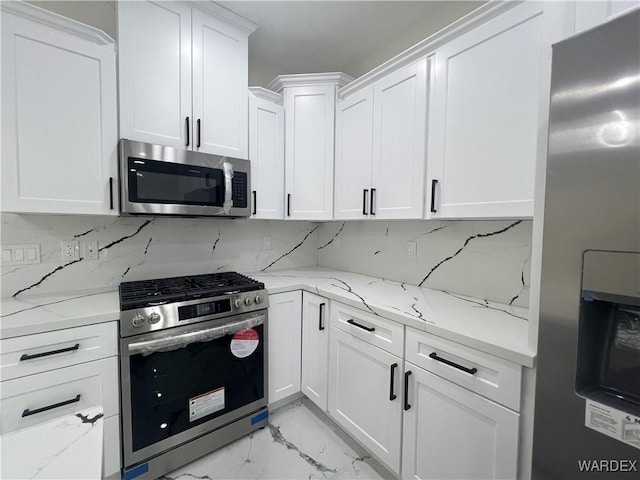 kitchen with stainless steel appliances, white cabinets, decorative backsplash, and light stone counters