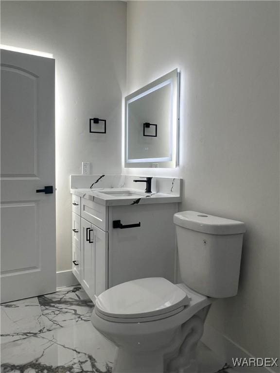 bathroom featuring toilet, marble finish floor, vanity, and baseboards