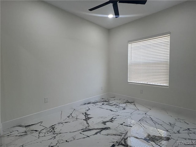 unfurnished room with a ceiling fan, marble finish floor, and baseboards