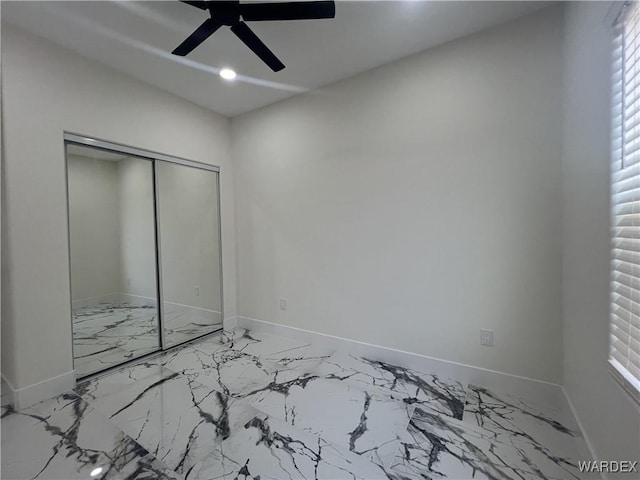 unfurnished bedroom with a ceiling fan, a closet, marble finish floor, and baseboards