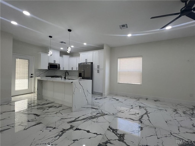 kitchen with a center island with sink, visible vents, appliances with stainless steel finishes, white cabinetry, and pendant lighting