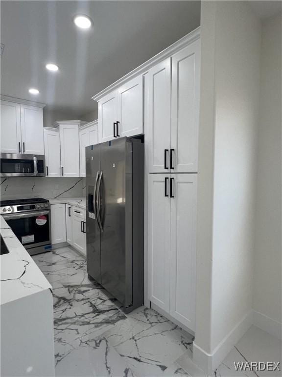 kitchen with recessed lighting, stainless steel appliances, white cabinetry, marble finish floor, and light stone countertops