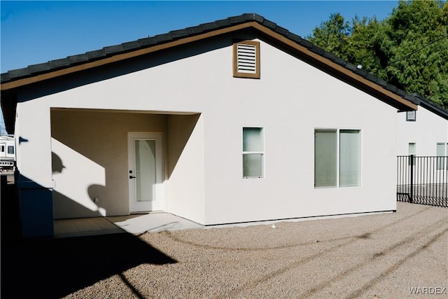 rear view of house with fence and stucco siding