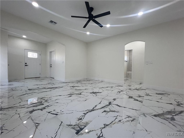 interior space featuring arched walkways, a ceiling fan, visible vents, and baseboards