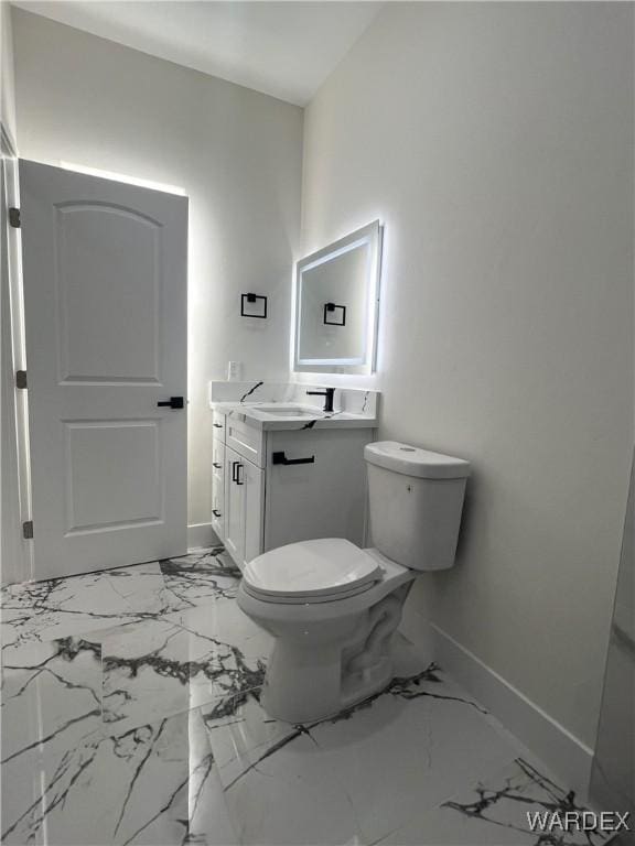 bathroom featuring toilet, marble finish floor, baseboards, and vanity