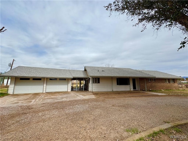 ranch-style home featuring an attached carport, driveway, and roof with shingles