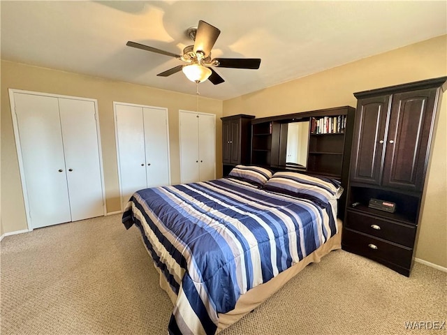 bedroom featuring light carpet, baseboards, two closets, and ceiling fan