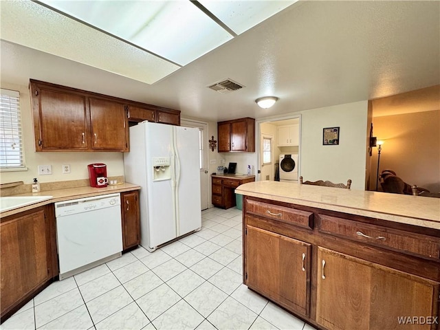 kitchen with visible vents, white appliances, washer / dryer, and light countertops