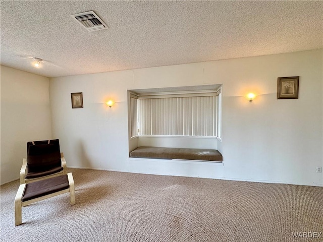 unfurnished room with carpet flooring, visible vents, and a textured ceiling