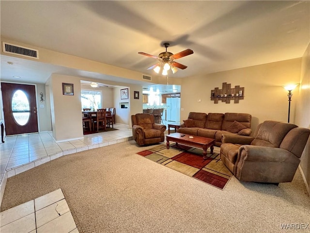 living area featuring light tile patterned floors, visible vents, light carpet, and a ceiling fan