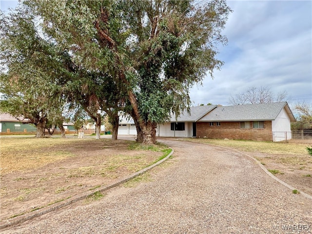 view of front of home featuring fence, brick siding, and driveway