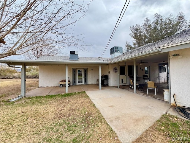 rear view of property with a patio, cooling unit, a ceiling fan, a chimney, and stucco siding