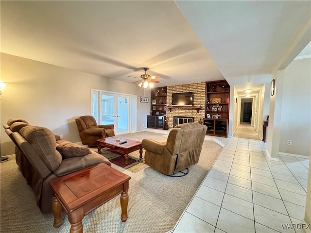 living area featuring built in shelves, french doors, light tile patterned flooring, a fireplace, and ceiling fan