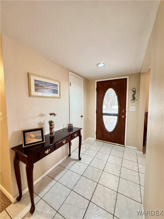 entryway featuring light tile patterned floors, arched walkways, and baseboards