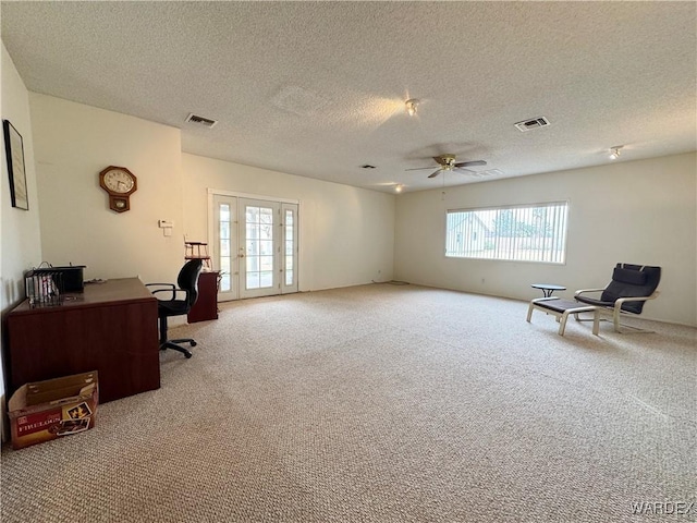 carpeted office with french doors, a textured ceiling, visible vents, and ceiling fan