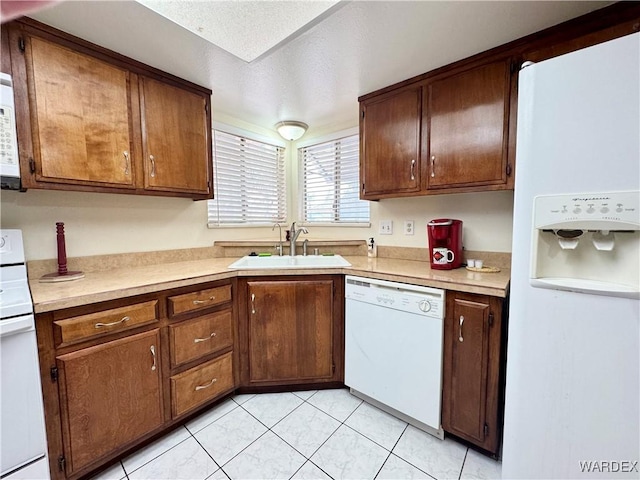 kitchen featuring white appliances, light tile patterned floors, a sink, light countertops, and a textured ceiling