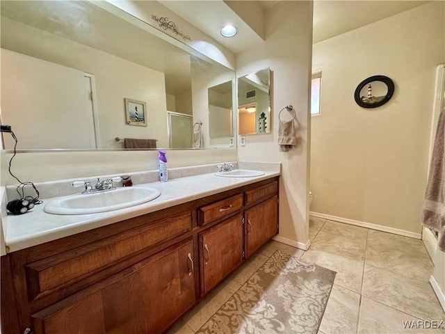 bathroom featuring tile patterned flooring, double vanity, a stall shower, and a sink