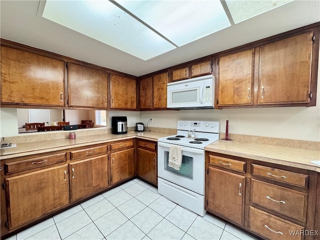 kitchen with white appliances, light tile patterned flooring, brown cabinetry, and light countertops