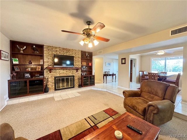 carpeted living room featuring visible vents, a brick fireplace, ceiling fan, built in features, and tile patterned floors