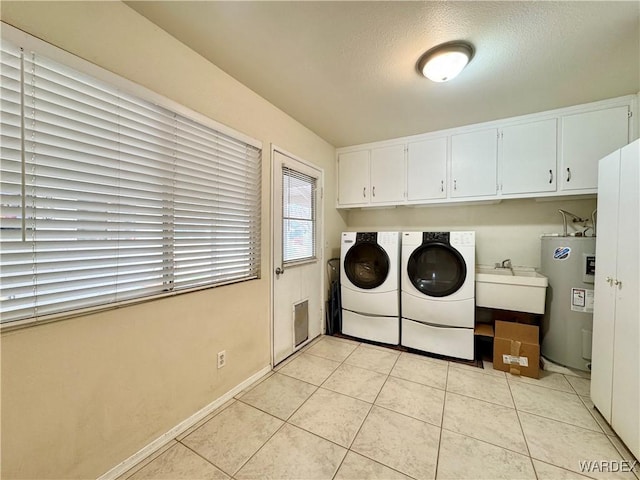 laundry area featuring light tile patterned floors, cabinet space, water heater, a sink, and washer and dryer