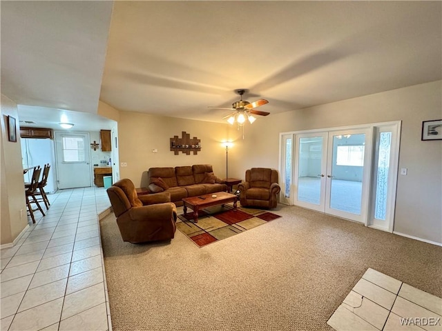 living area with baseboards, ceiling fan, light tile patterned floors, light carpet, and french doors